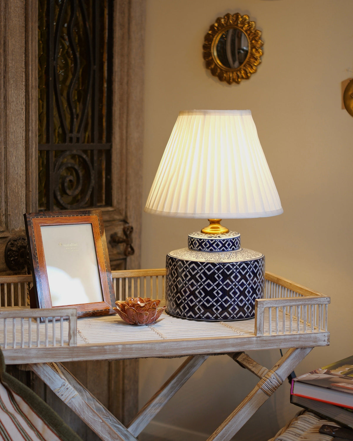 Lamp on a decorative table with a mirror and decorative items in a room setting.