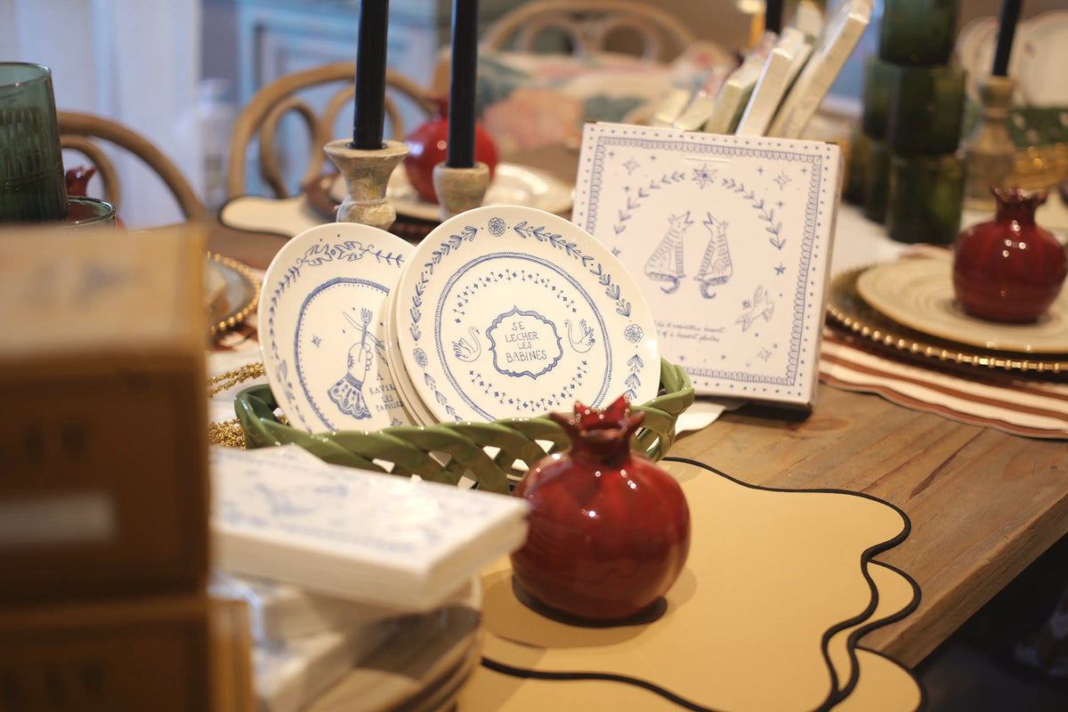 Decorative table setting with plates, candles, and a card on a wooden table.