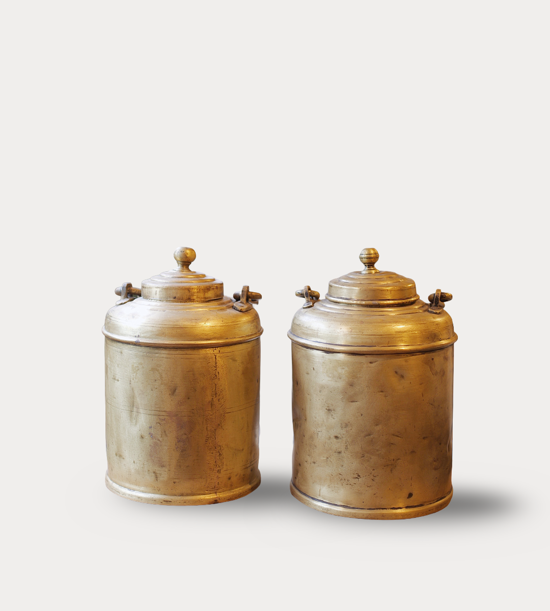 Two brass canisters with lids on a light gray background
