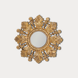 Decorative gold mirror with intricate patterns on a light gray background