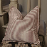 Striped pillow on a wicker chair with a neutral background