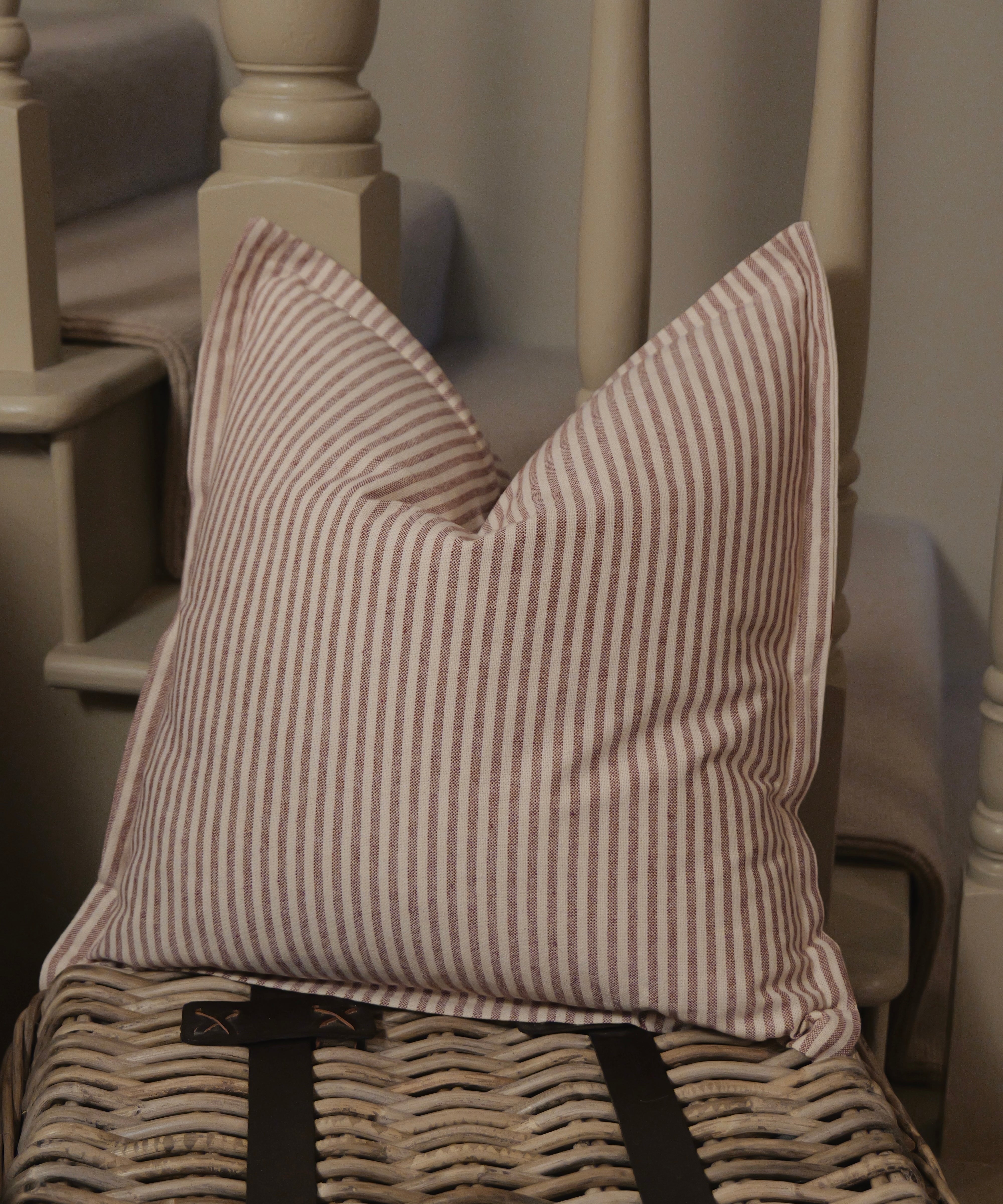 Striped pillow on a wicker chair with a neutral background