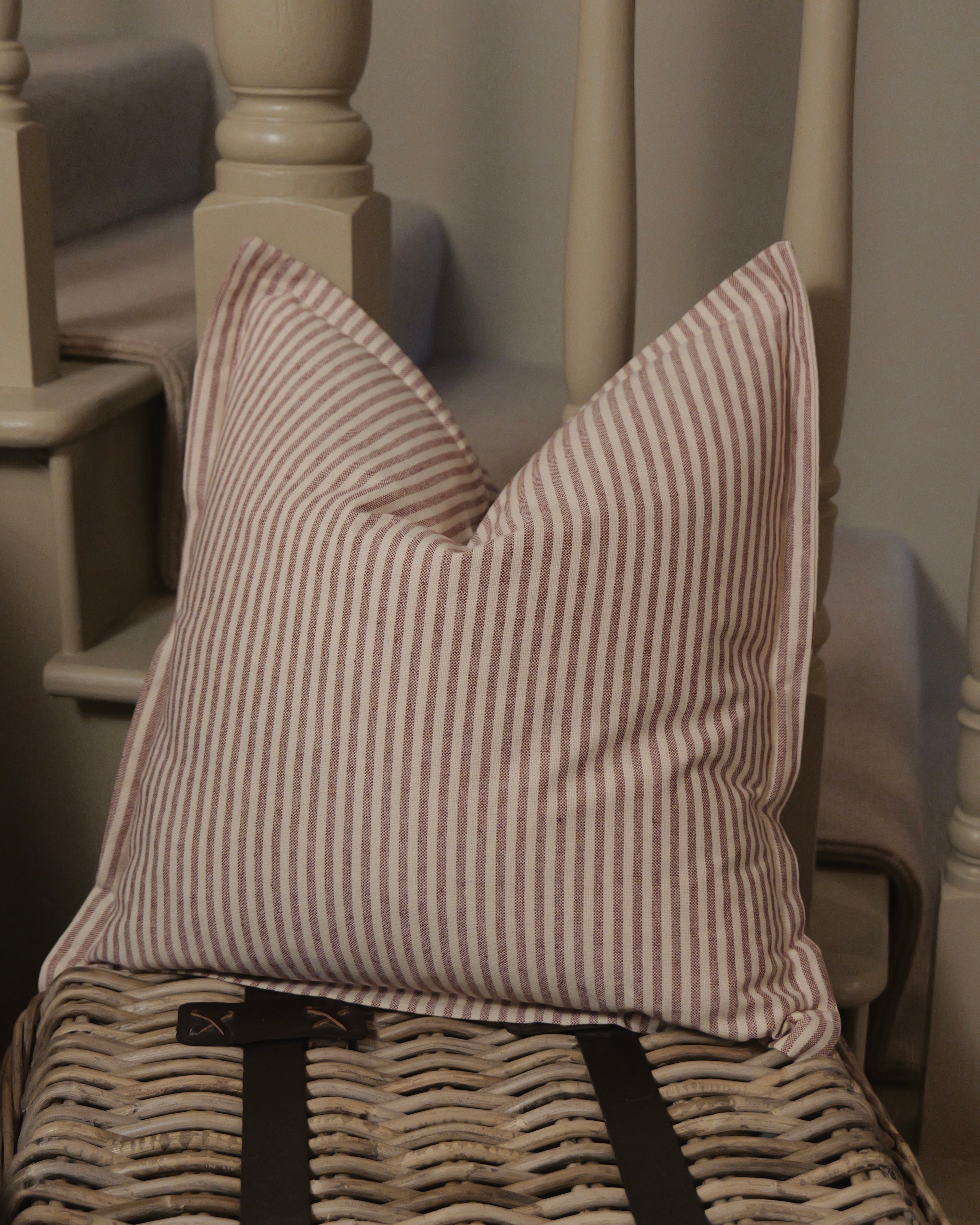 Striped pillow on a wicker chair with a neutral background