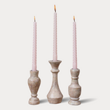 Three candlesticks with pink candles on a light gray background