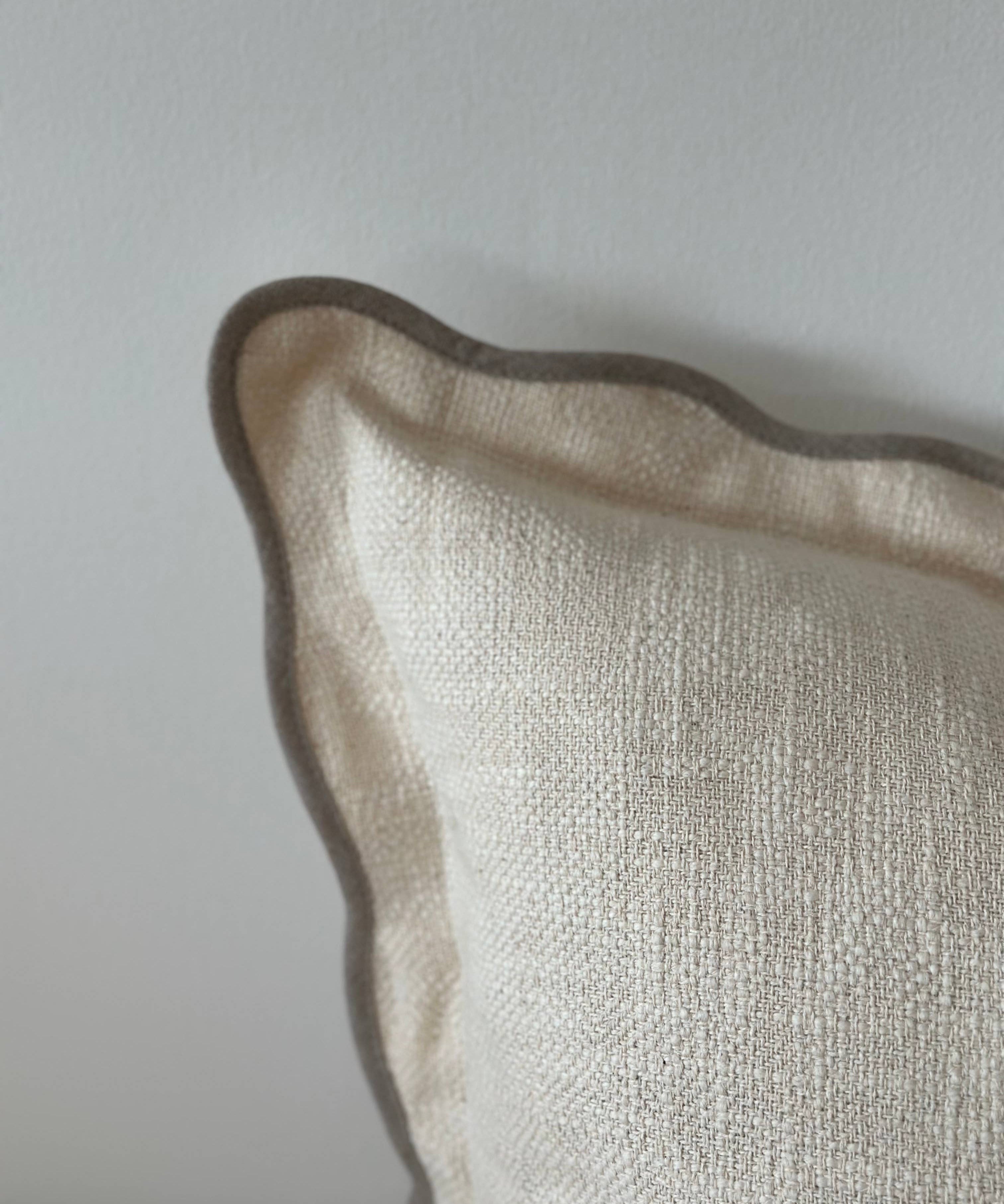 Close-up of a textured beige pillow against a light gray background
