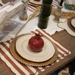 Decorative table setting with pomegranates, plates, and a book on a wooden table.