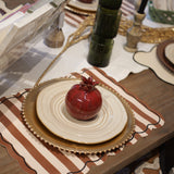 Decorative table setting with pomegranates, plates, and a book on a wooden table.