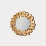 Decorative gold mirror with a floral frame on a light gray background