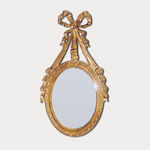 Decorative gold mirror with a bow-like design on a white background
