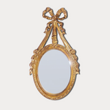 Decorative gold mirror with a bow-like design on a white background