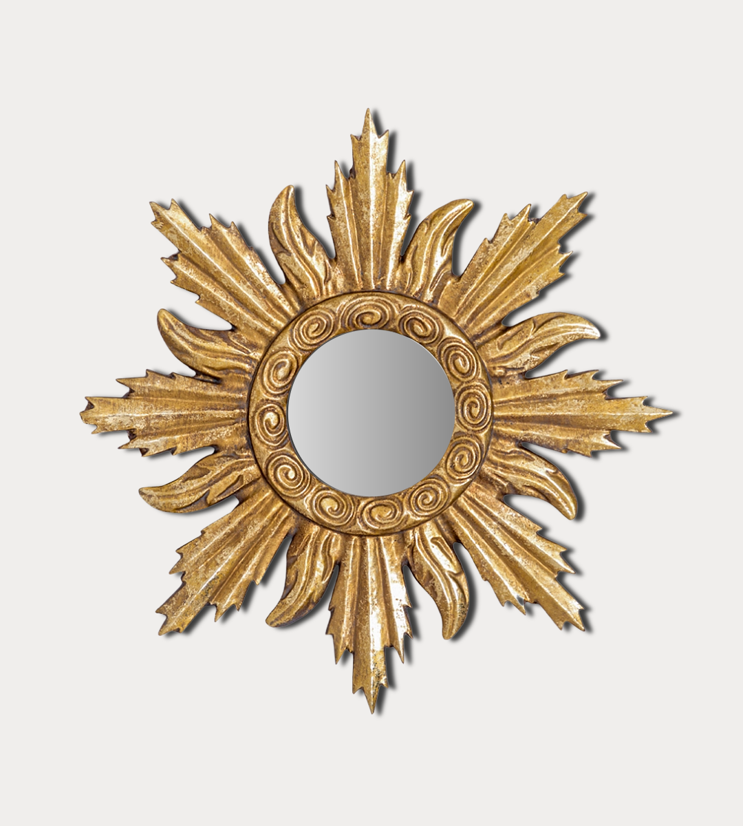 Decorative gold sunburst mirror on a light gray background