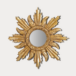 Decorative gold sunburst mirror on a light gray background