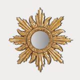Decorative gold sunburst mirror on a light gray background