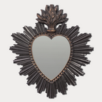Decorative wall mirror with heart shape and sunburst frame on a light gray background