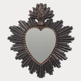 Decorative wall mirror with heart shape and sunburst frame on a light gray background