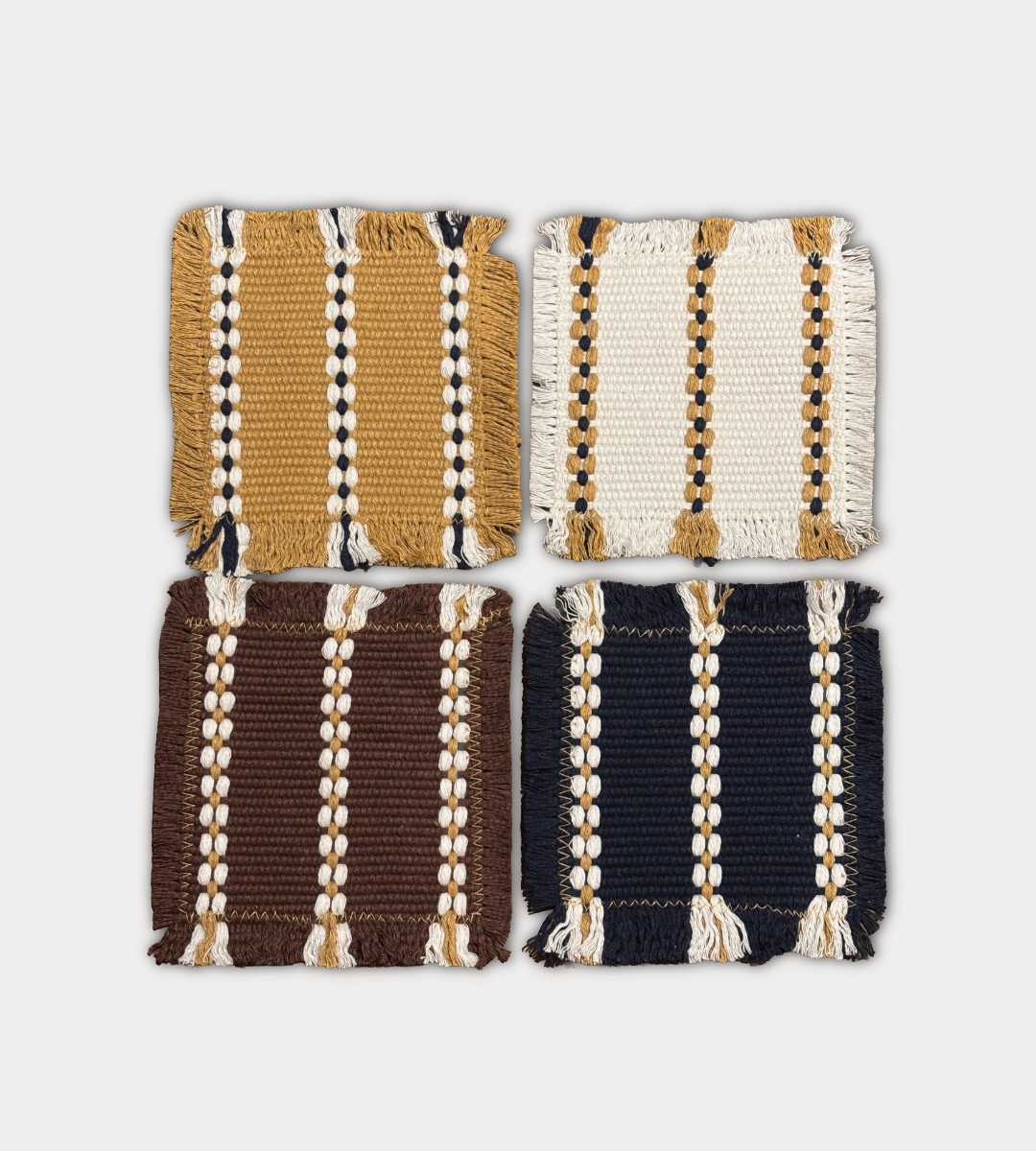 Four square woven textile swatches arranged in a 2x2 grid on a light gray background. The top-left swatch is mustard yellow with cream and black stripes; the top-right is off-white with cream and mustard stripes; the bottom-left is dark brown with cream and mustard stripes; the bottom-right is dark navy blue with cream and mustard stripes.