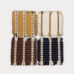 Four square woven textile swatches arranged in a 2x2 grid on a light gray background. The top-left swatch is mustard yellow with cream and black stripes; the top-right is off-white with cream and mustard stripes; the bottom-left is dark brown with cream and mustard stripes; the bottom-right is dark navy blue with cream and mustard stripes.