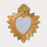 Heart-shaped mirror with gold sunburst frame on a light gray background