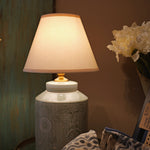 Decorative lamp with a textured base on a table against a neutral wall.