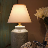 Decorative lamp with a textured base on a table against a neutral wall.