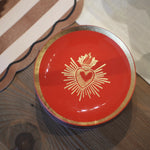Red dish with gold emblem on a wooden surface