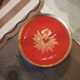 Red dish with gold emblem on a wooden surface