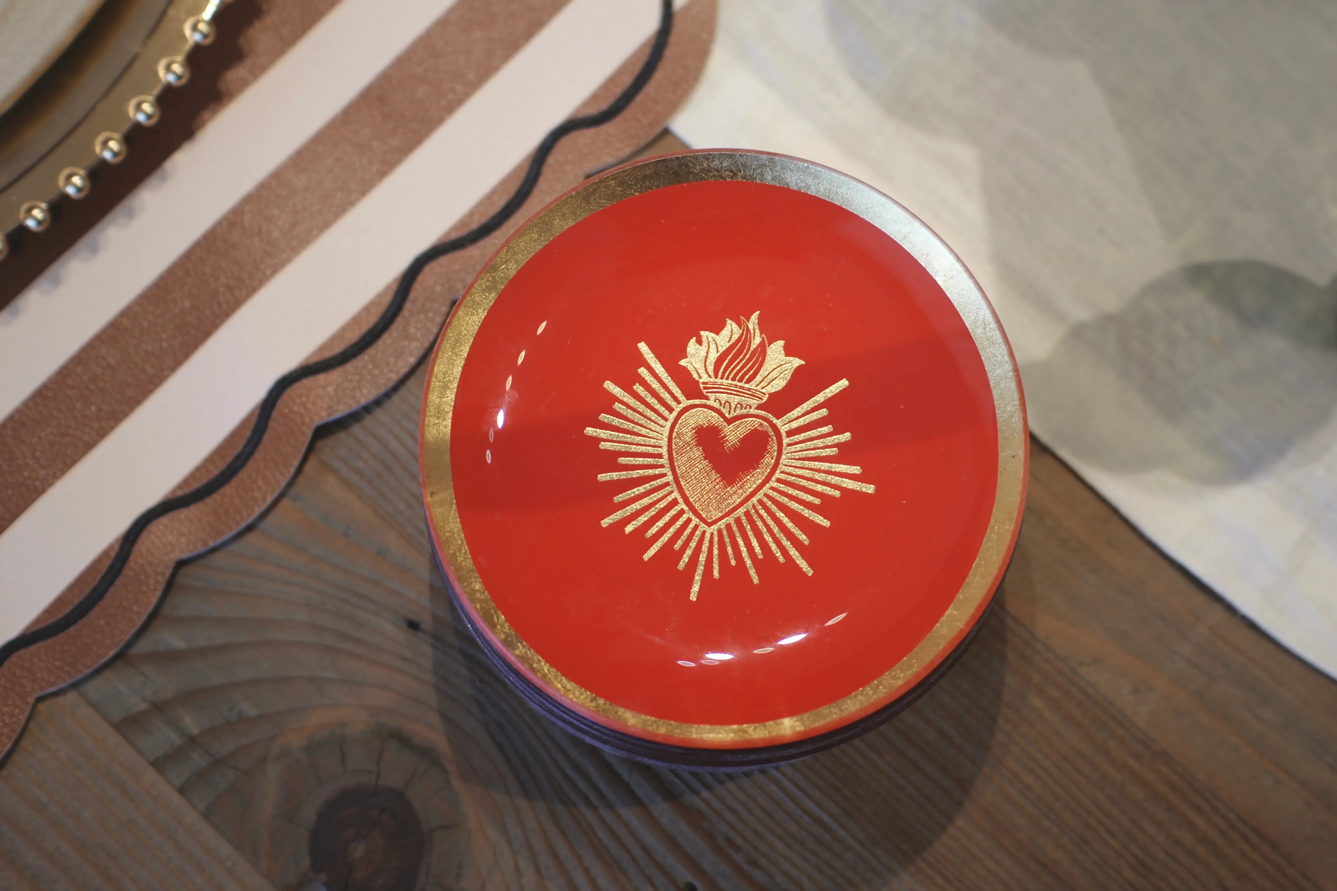 Red dish with gold emblem on a wooden surface