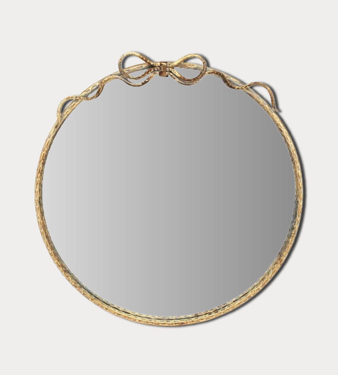 Round mirror with a gold frame on a light gray background