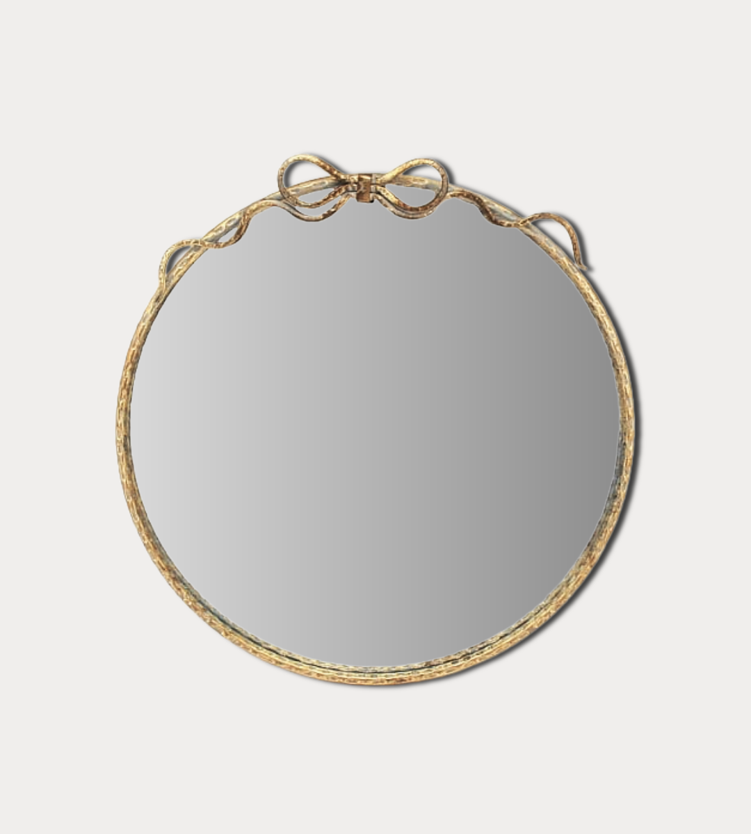 Round mirror with gold frame on a light gray background