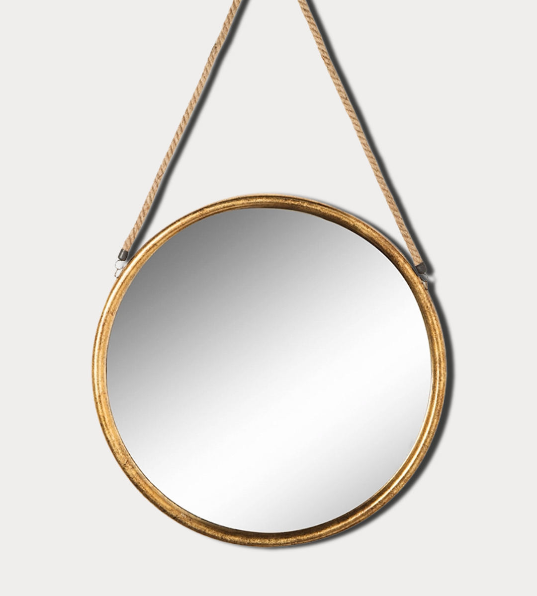 Round mirror with gold frame hanging on a white wall