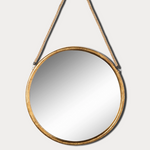 Round mirror with gold frame hanging on a white wall