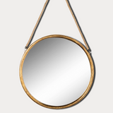 Round mirror with gold frame hanging on a white wall