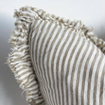 Textured pillow with striped pattern and ruffled edge on a neutral background