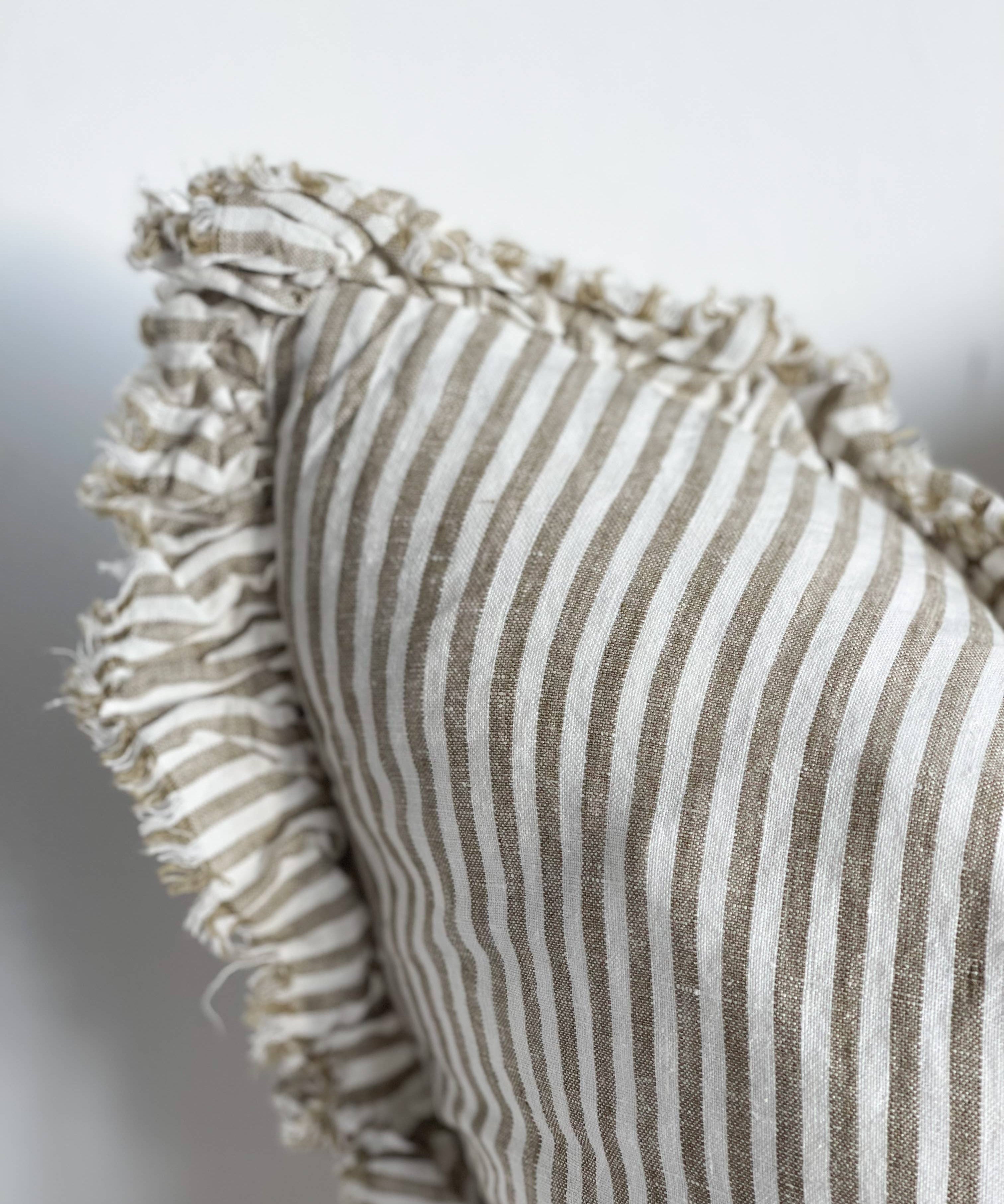 Textured pillow with striped pattern and ruffled edge on a neutral background