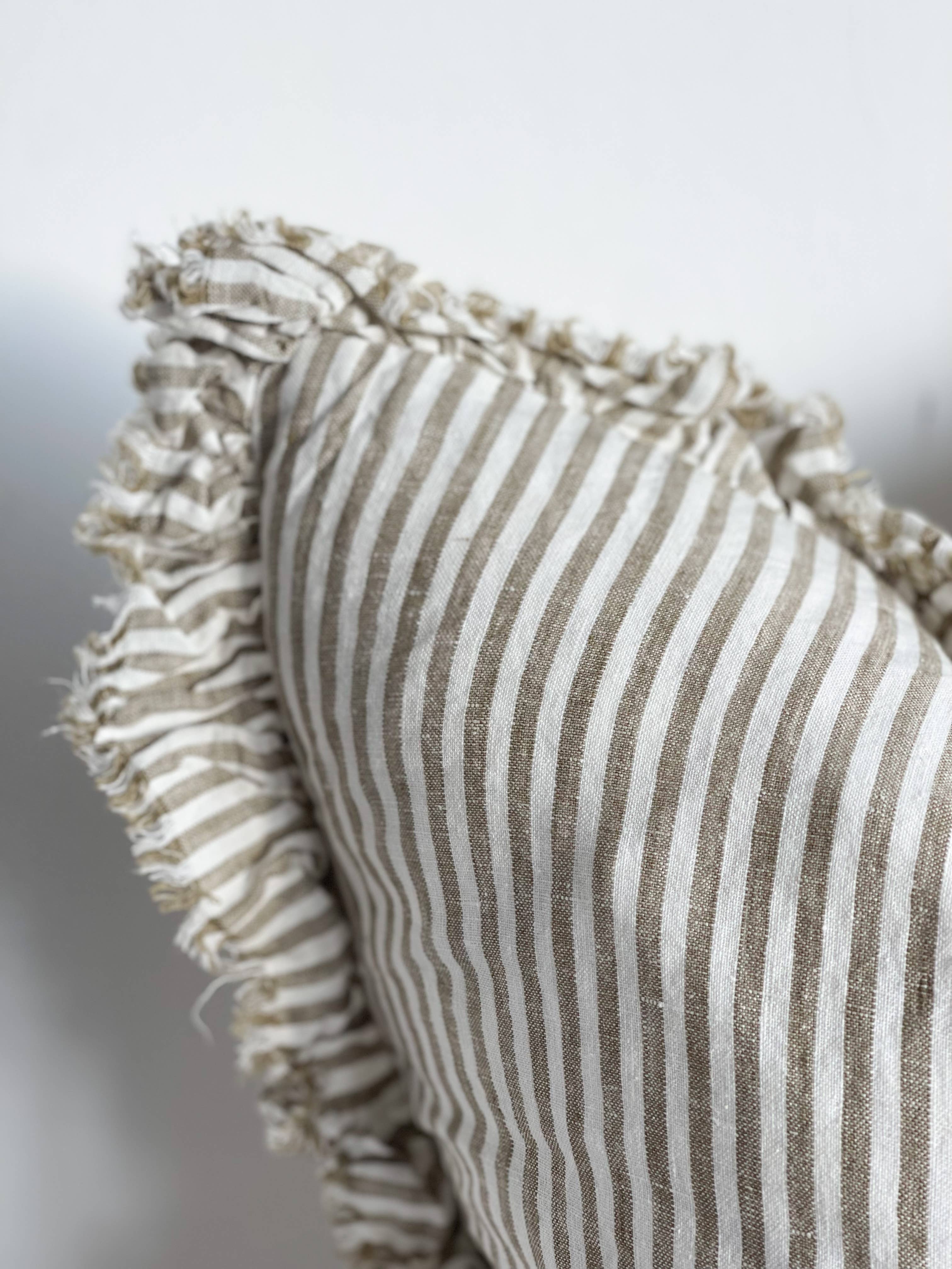 Textured pillow with striped pattern and ruffled edge on a neutral background