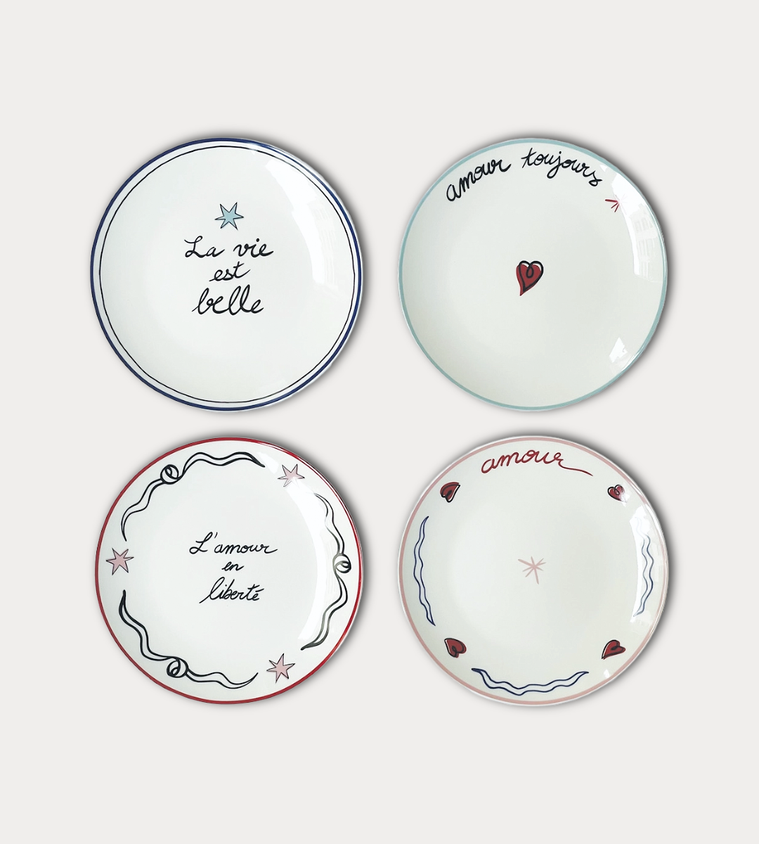 Four decorative plates with French phrases on a white background