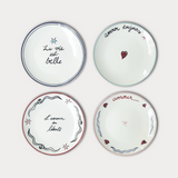 Four decorative plates with French phrases on a white background