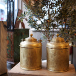 Two gold cylindrical objects on a wooden surface with a blurred background