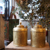 Two gold cylindrical objects on a wooden surface with a blurred background