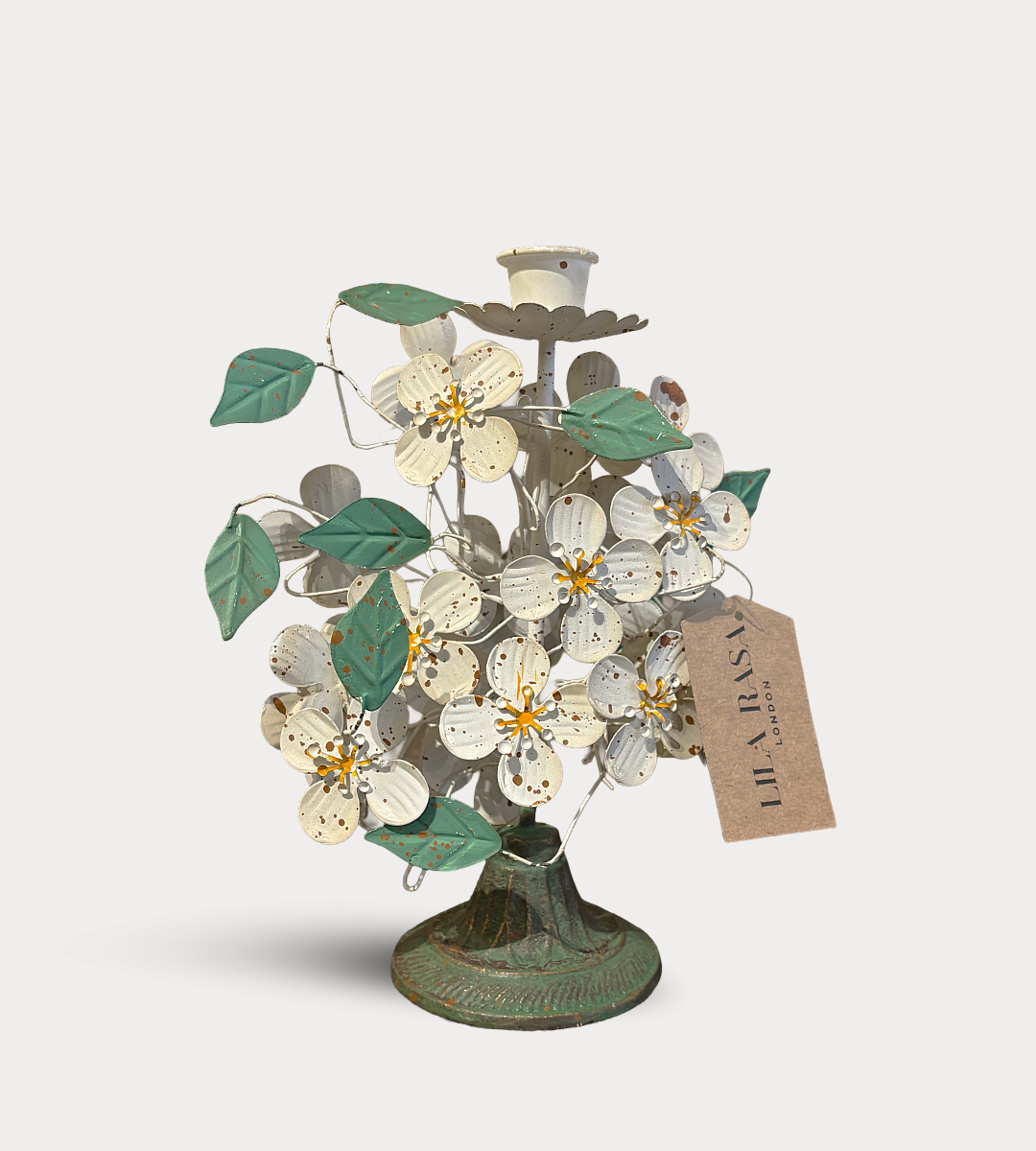 Decorative metal tree with flowers and a tag on a white background