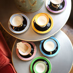 Set of colorful teacups and saucers on a round table with a decorative canister.
