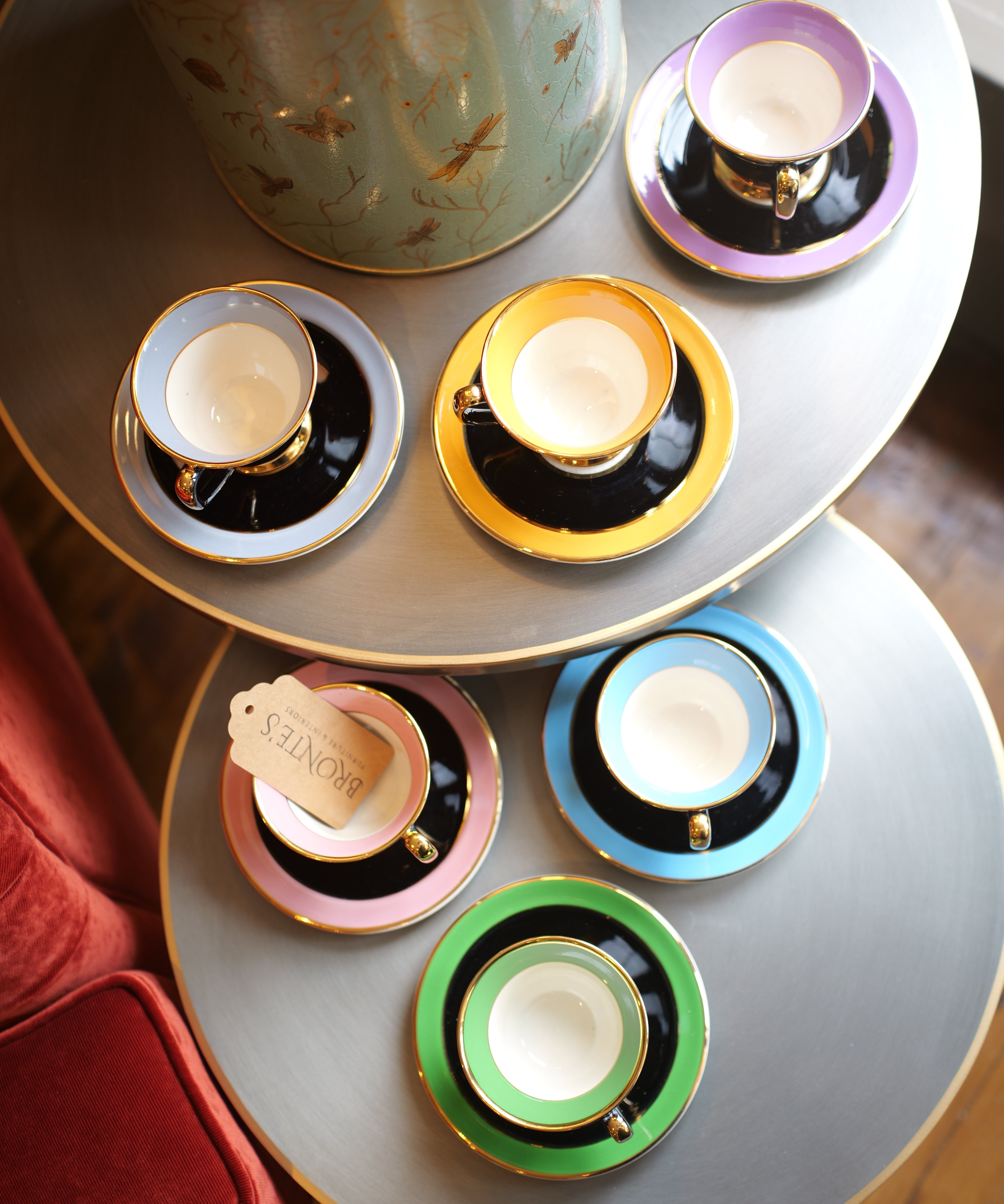 Set of colorful teacups and saucers on a round table with a decorative canister.