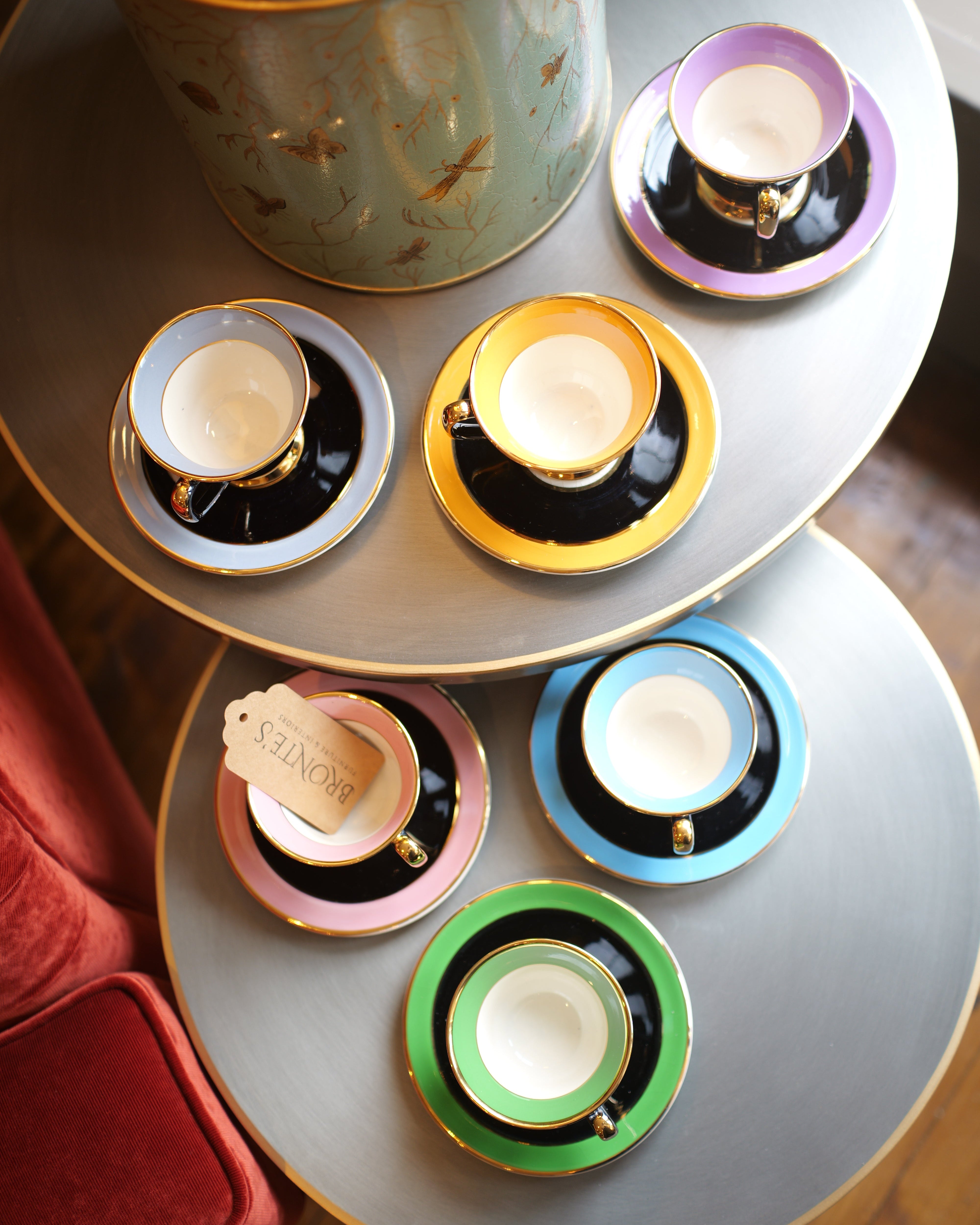 Set of colorful teacups and saucers on a round table with a decorative canister.