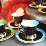 Teacups and saucers on a table with a red cushioned chair in the background