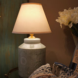 Decorative lamp with a textured base on a table against a neutral wall.