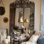 Living room with ornate mirror, striped sofa, and decorative pillows.