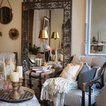 Living room with ornate mirror, striped sofa, and decorative pillows.