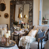 Living room with ornate mirror, striped sofa, and decorative pillows.
