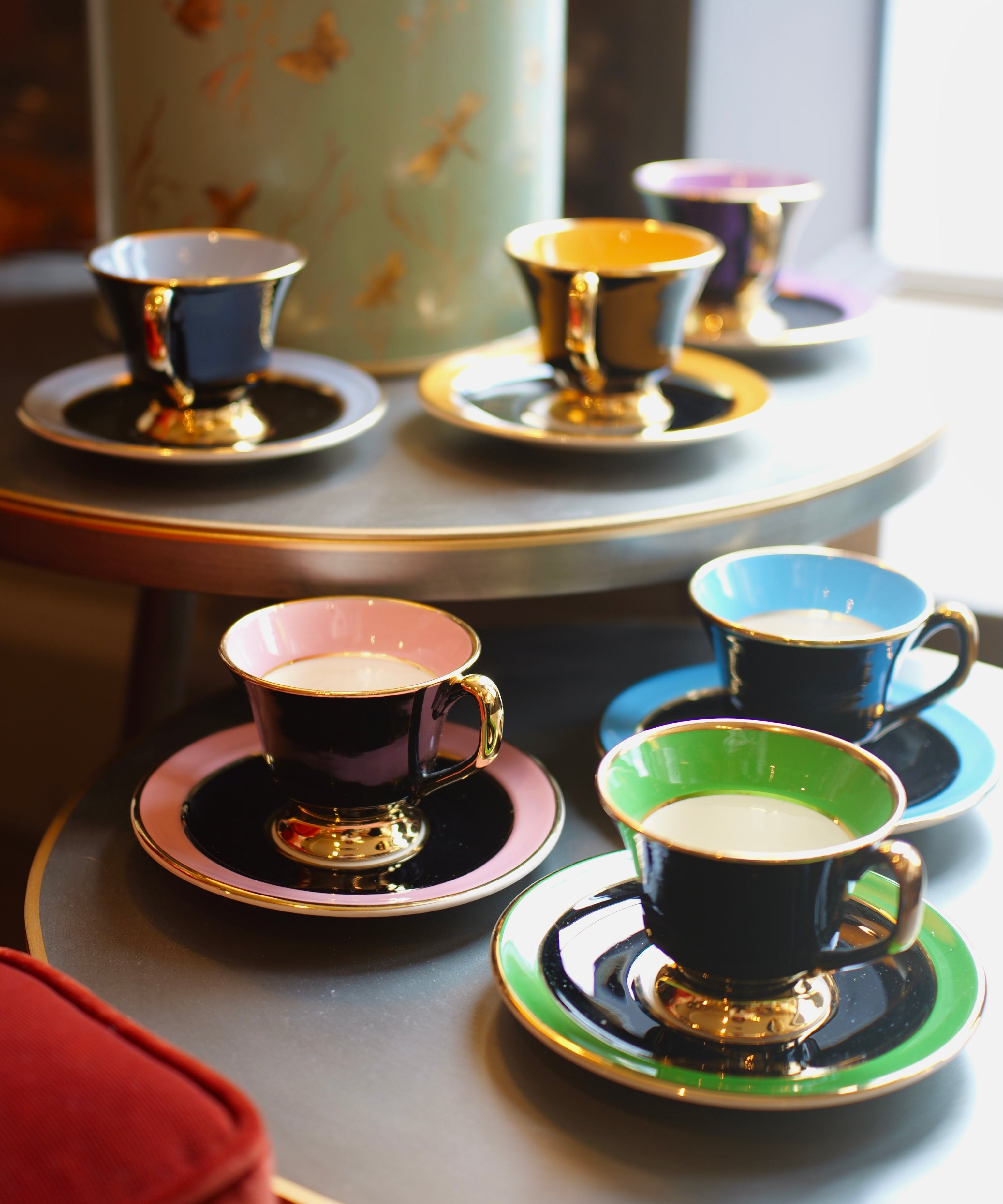 Colorful teacups and saucers on a table with a decorative canister in the background.
